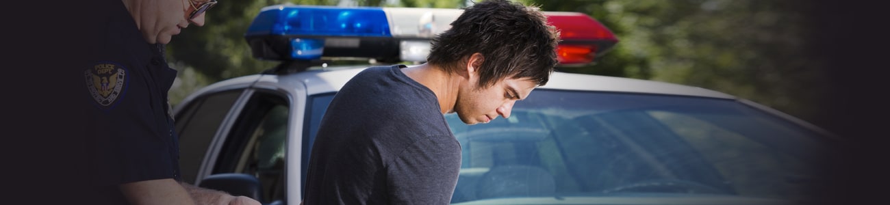 Banner picture of the police officer putting handcuffs on young person